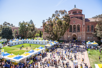 Crowds of people visit booths and walk around outside Powell Library on Bruin Day.